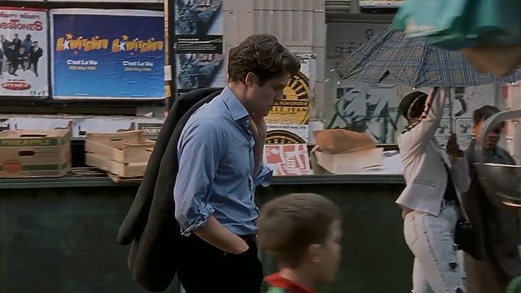 A man in a blue shirt walks past the stalls of a street market.