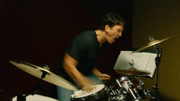 A drummer plays intensely at his drum kit.