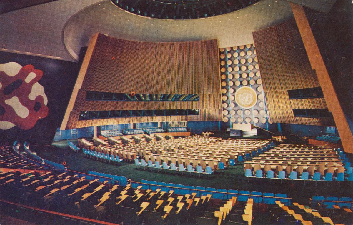 Rows of seats facing a podium in a large assembly hall.